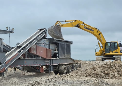 Excavator loading rock into a Superior Sentry® HSI portable crushing plant at an aggregate processing site.