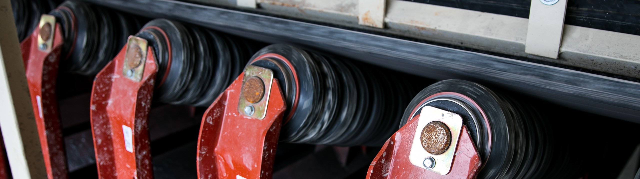 Rubber impact idler rolls supporting a conveyor belt at the load zone