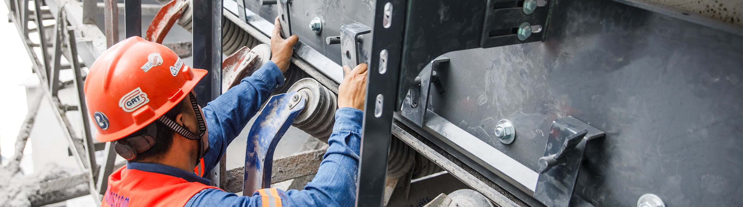 Worker installing a conveyor skirting system at a mine in Mexico to control dust and material spillage at a transfer point