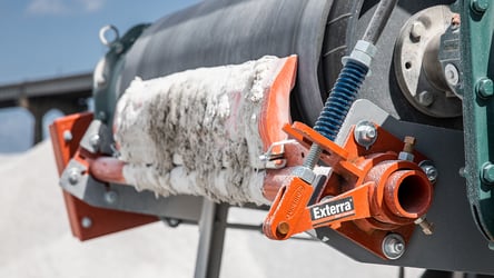 Material-filled belt cleaner on head pulley of conveyor