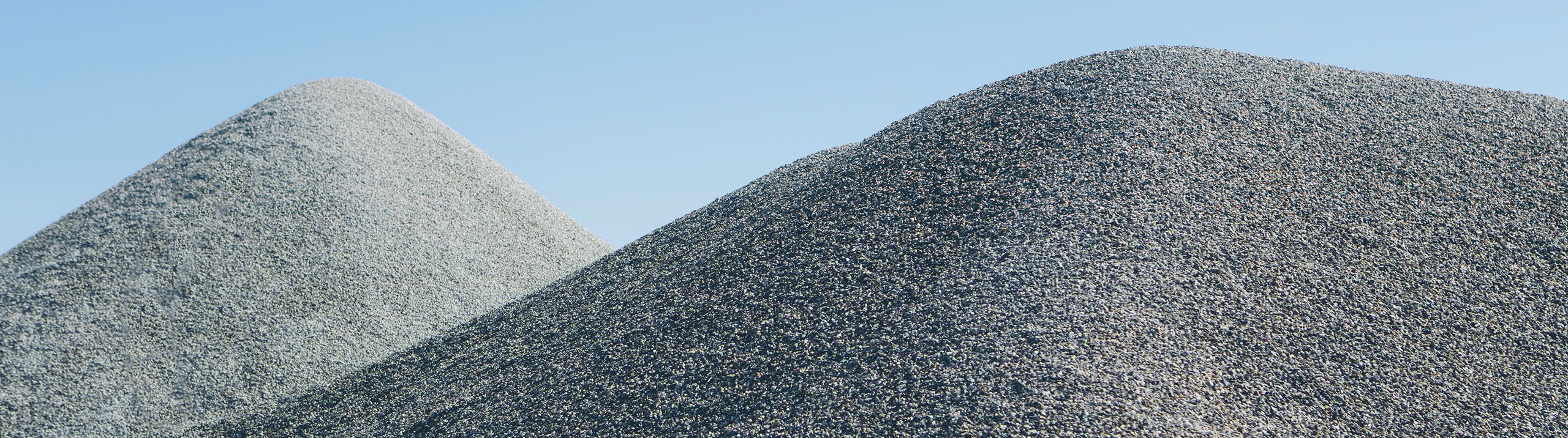 Stockpiles of fine aggregate sand produced at a quarry, showing two large piles of screened fine material used in construction and concrete applications.