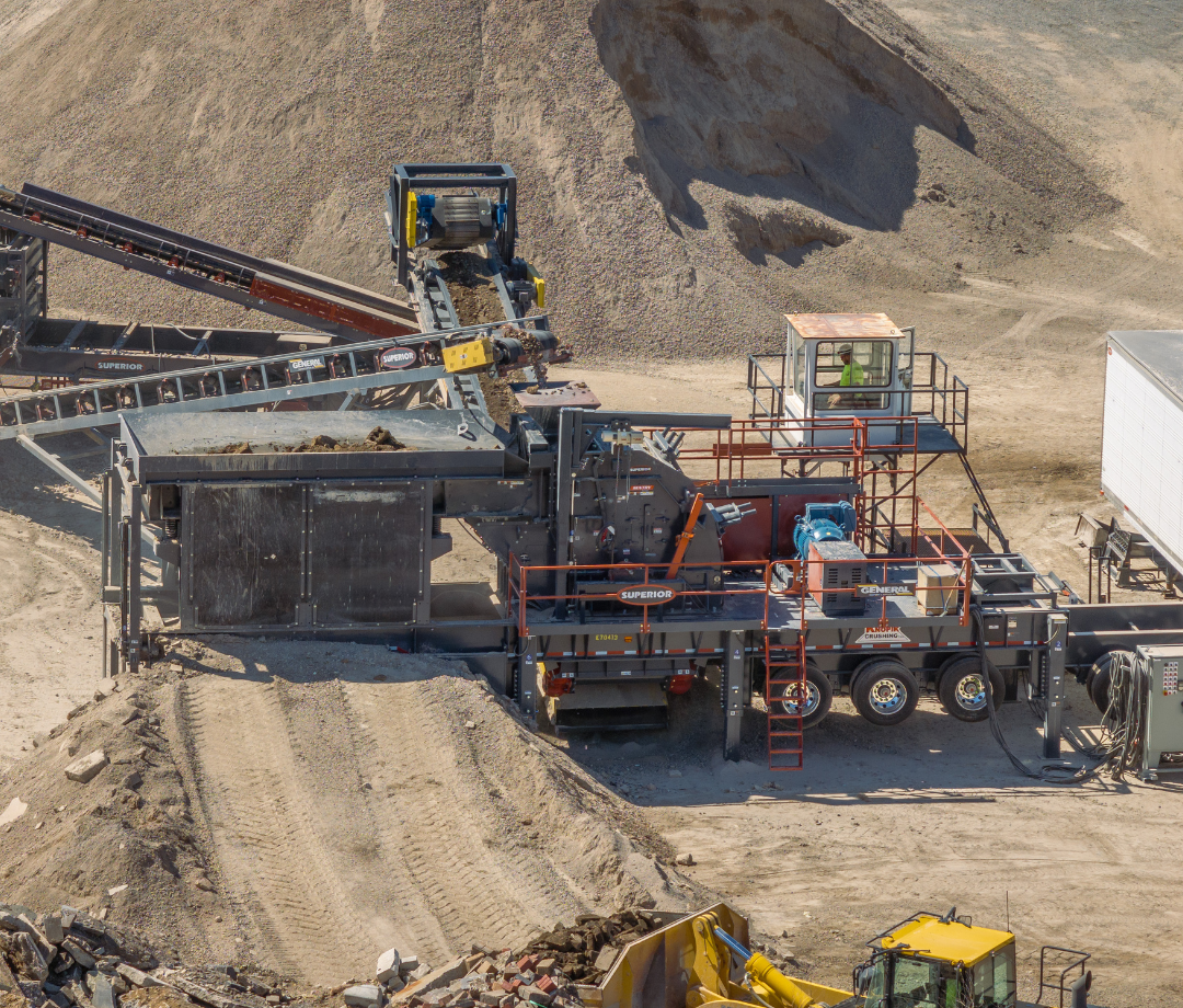 Worker in safety vest standing on platform beside Superior® Sentry® HSI at active mobile crushing site