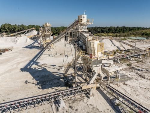 Aggregate plant with overland conveyors and stacking equipment designed to reduce material handling