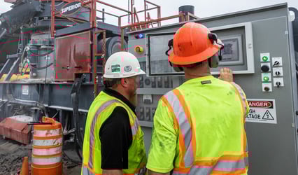 Two quarry workers adjust the settings on the automation panel of a portable crushing plant from Superior.