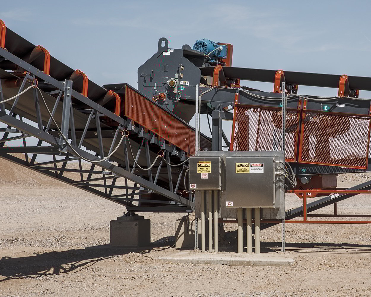 Conveyor transfer point with safety guarding and skirting system installed to contain dust and material spillage