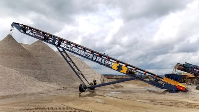 Superior® Radial Stacking Conveyor depositing processed material into a conical stockpile at an aggregate site.