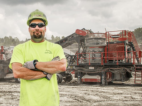 Operator in front of a Patriot® Cone Crusher, highlighting warranty protection for major crusher components