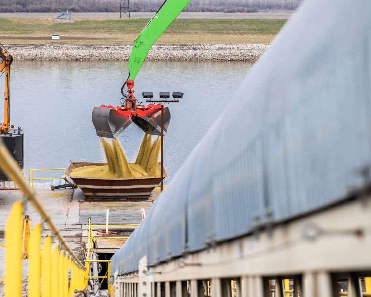 Crane/backhoe unloading potash into a conveyor hopper