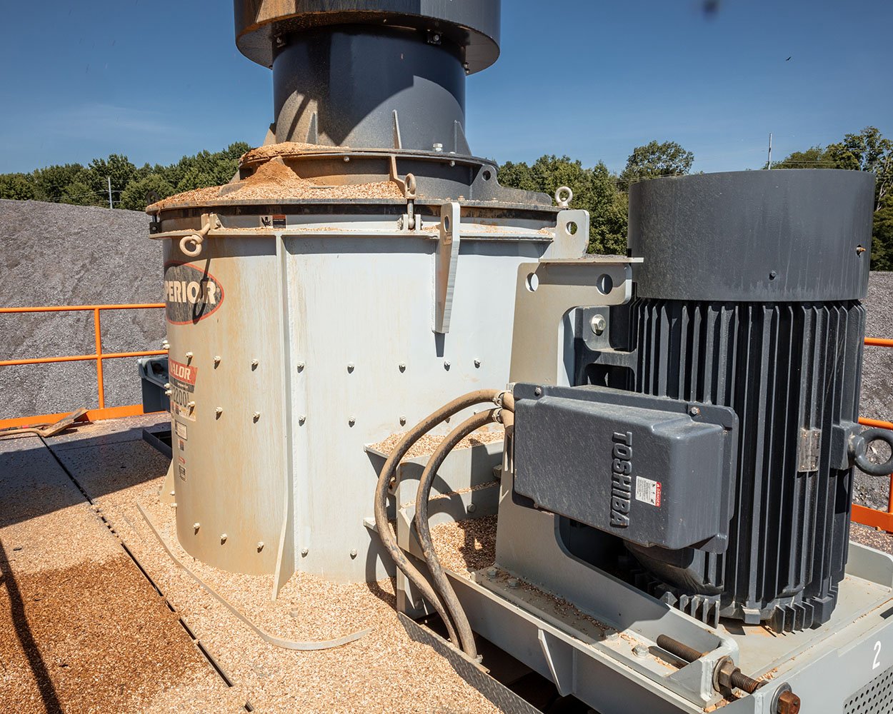 Material feeding into Superior® Valor® VSI Crusher under clear blue sky producing spec material on-site
