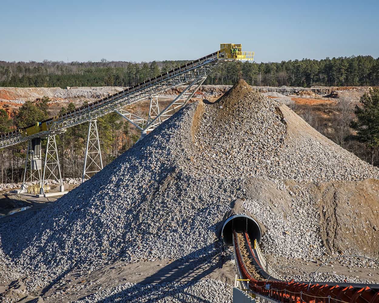 Surge Tunnel Reclaim Conveyor operating beneath large rock pile at South Carolina quarry site