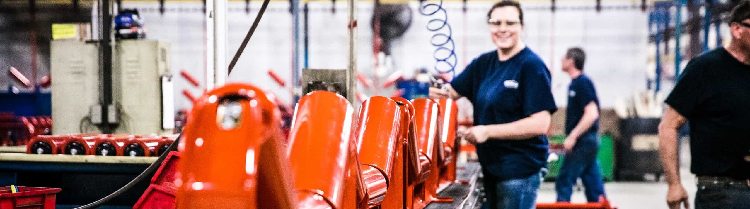 Employee at Superior manufacturing plant preparing replacement steel idler rolls for shipment
