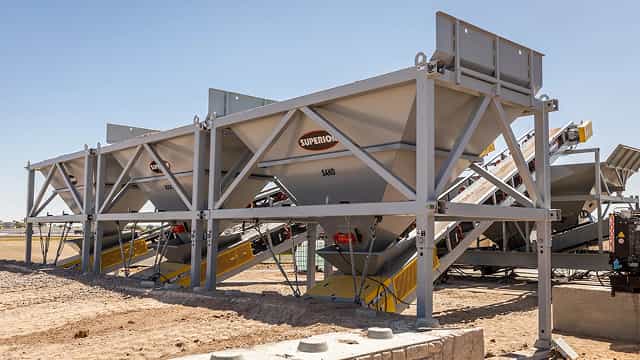 Superior® Feed Hoppers designed for controlled material flow onto conveyor belts at an aggregate site.