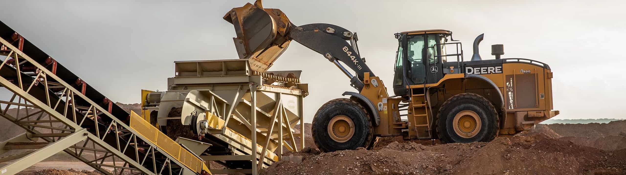 Payloader feeding a conveyor via feed hopper