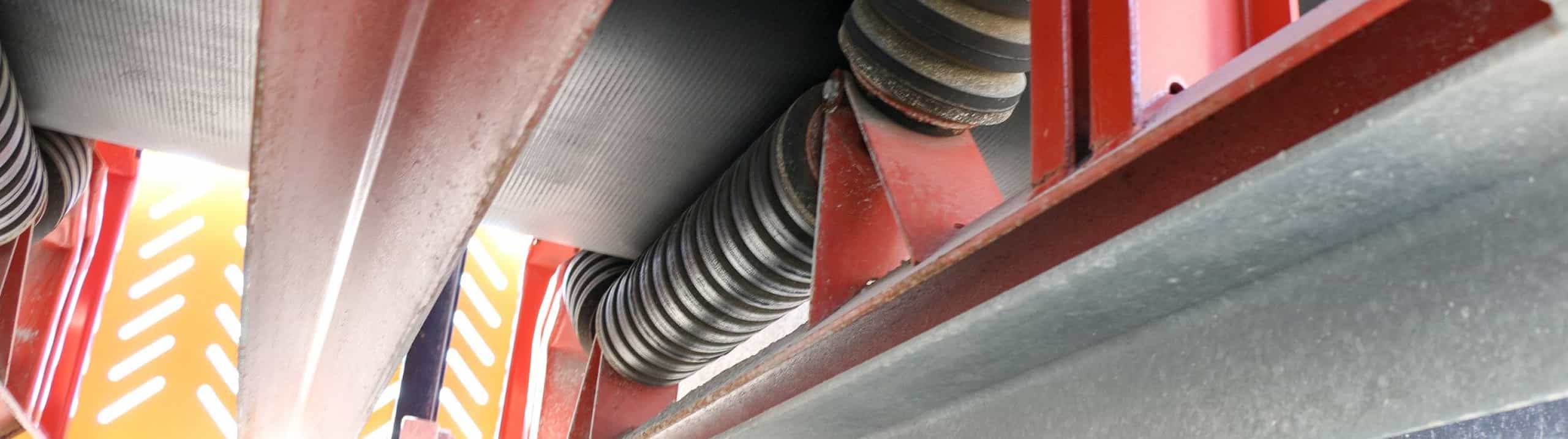 Rubber impact idler roll beneath conveyor belt closeup