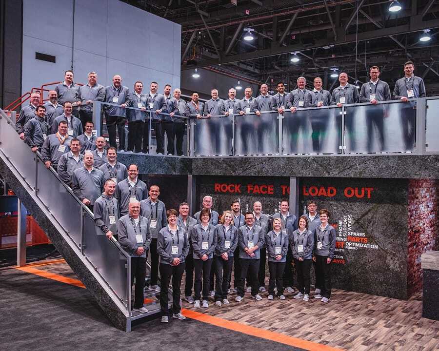 Large group of Superior Industries team members standing on a two-level display at CONEXPO-CON/AGG 2017.
