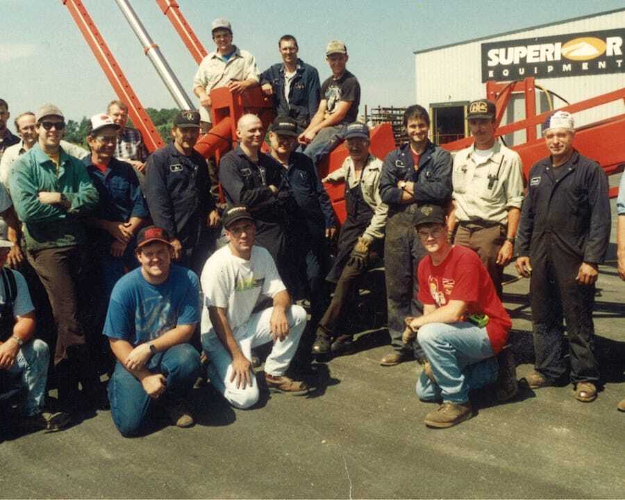 Group of Superior Industries employees posing outdoors with a conveyor.