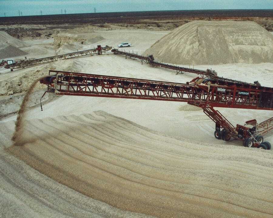 One of the first TeleStacker Conveyors stacking sand into tall piles at a large open pit site.