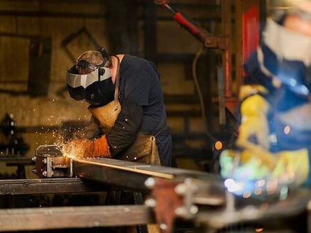 A welder fabricates a steel structure inside Superior’s manufacturing facility, representing the in-house fabrication phase of construction management