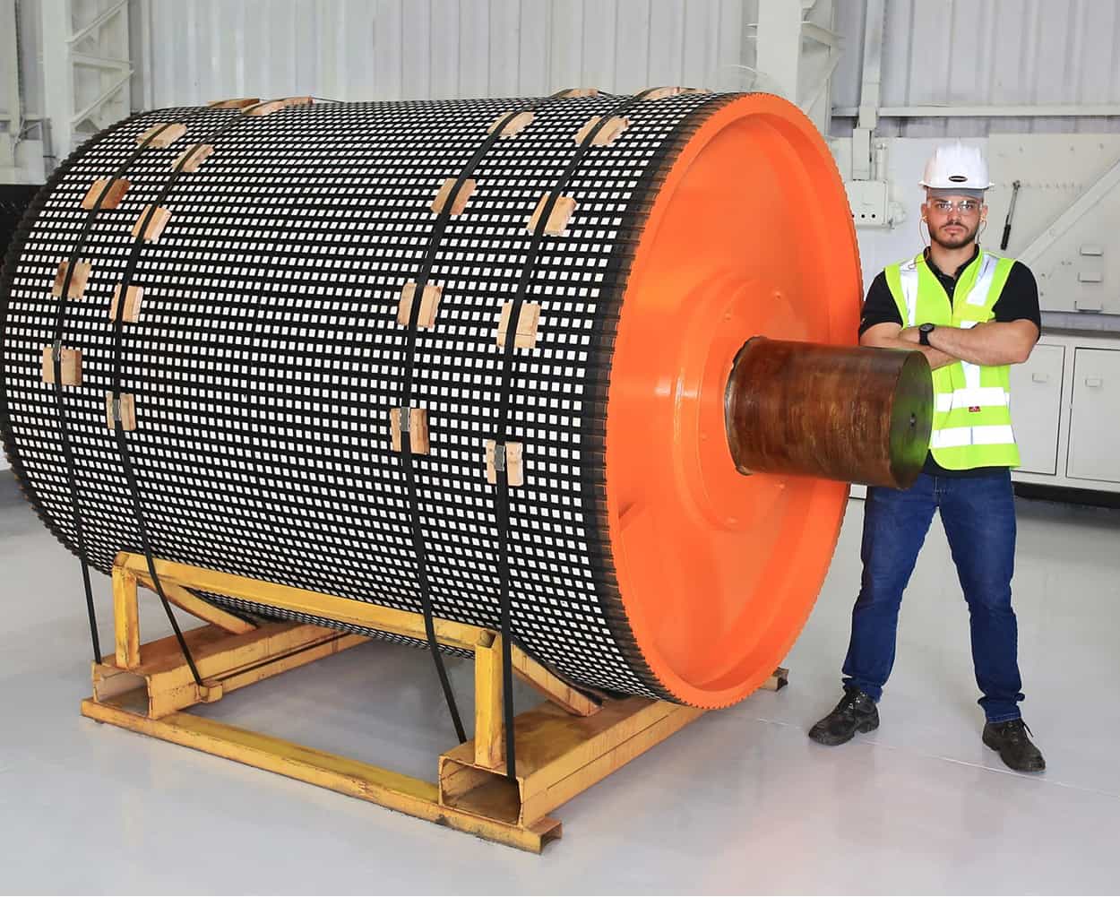 Engineer standing beside a large Superior conveyor pulley built for heavy-duty mining applications