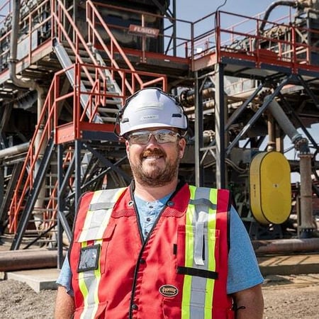 A construction manager wearing a hard hat and safety vest stands in front of a newly built aggregate processing plant, representing Superior’s single-source accountability from concept to completion
