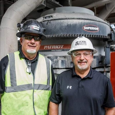 Two men wearing safety gear stand in front of a Superior Patriot cone crusher at York Building Products’ Thomasville, Pennsylvania