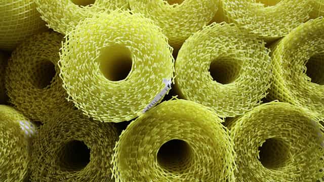 Close-up image of multiple yellow rolls of flexible safety guard mesh used for conveyor guarding applications.