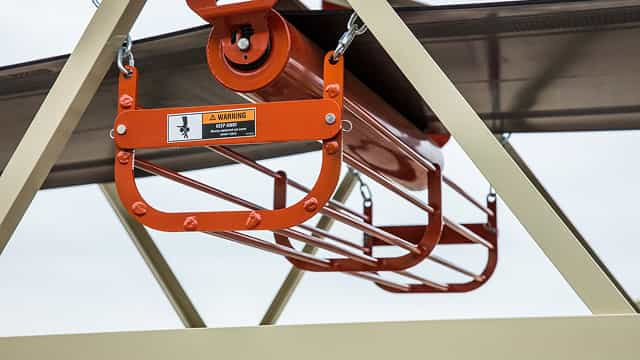 Close-up of a steel return idler guard basket mounted beneath a conveyor belt, designed to protect workers from moving return rolls and pinch points.