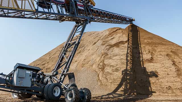 Superior® TeleStacker® Conveyor stockpiling sand at a quarry site, showcasing its automated radial stacking design for even material distribution.