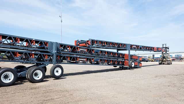 Superior® Portable Transfer Conveyors stacked and ready for transport, designed for flexible material transfer between processing equipment.